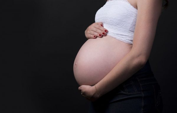 Беременная женщина держит руки на животе