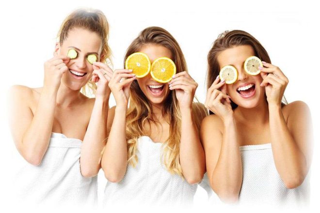 три девушки держат возле глаз кружочки фруктов и огурца